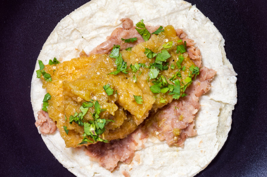 Pork rinds in green salsa with refried beans